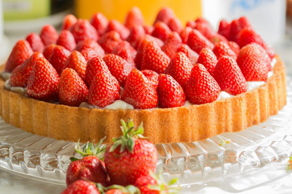 Ganze Erdbeeren auf einem Kuchenboden angeordnet und mit Tortenguss bedeckt